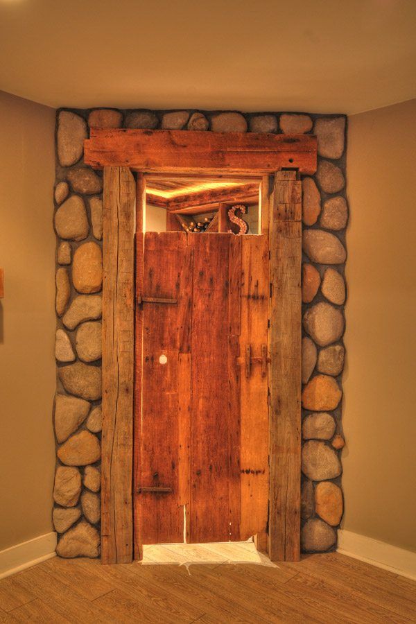 A wooden door is surrounded by stone in a room.