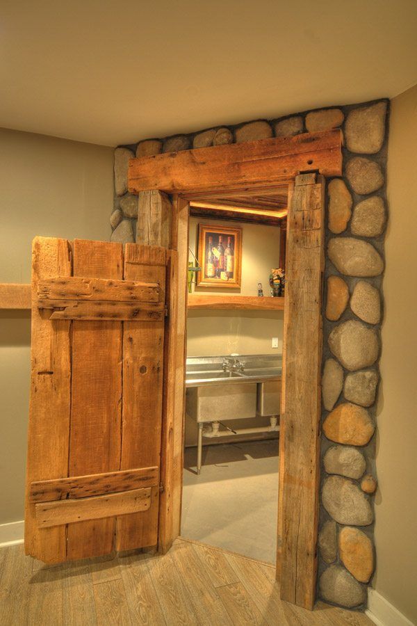 A wooden door is open to a room with a stone wall.