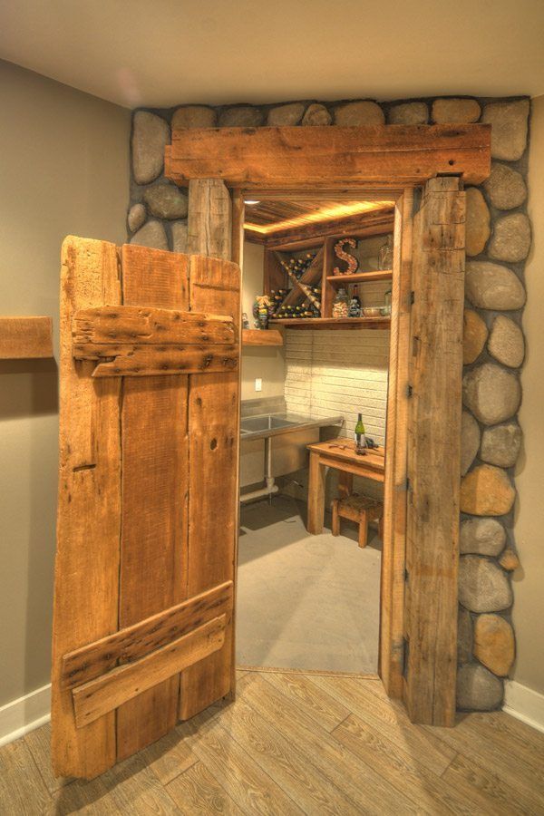 A wooden door is open to a room with a stone wall.
