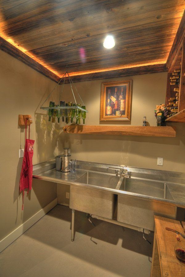 A kitchen with a stainless steel sink and a wooden ceiling.
