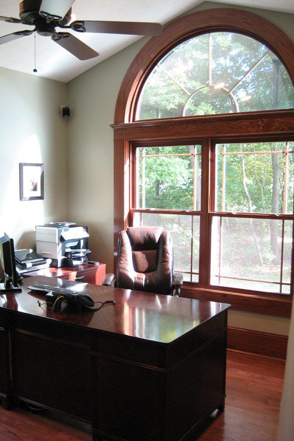 An office with a ceiling fan and a large window