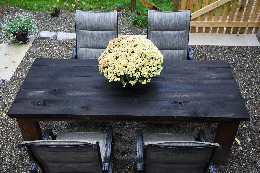 A table with chairs and a vase of flowers on it