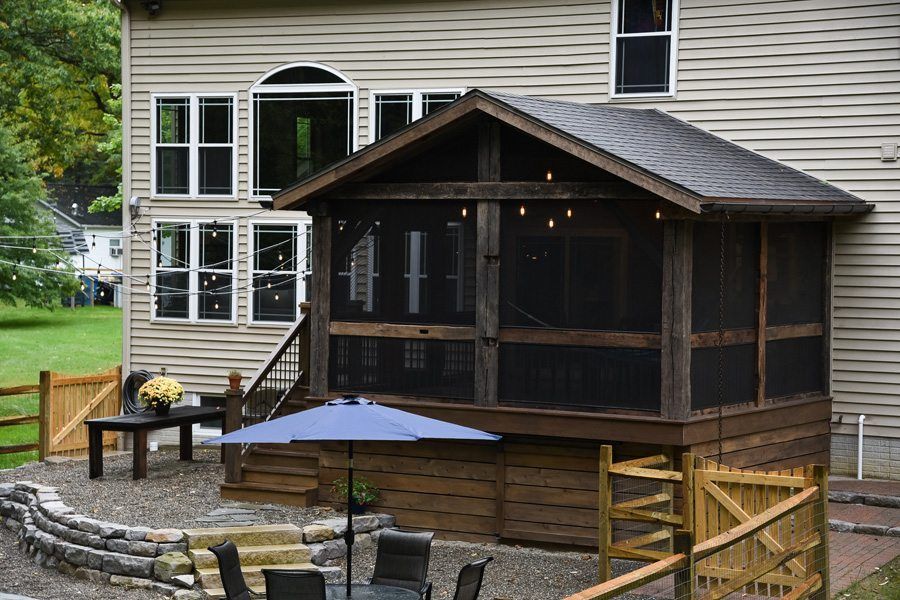 A screened in porch with a blue umbrella in front of a house.