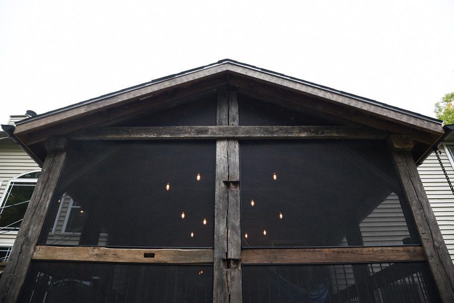 A screened in porch with a wooden roof and lights on the ceiling.