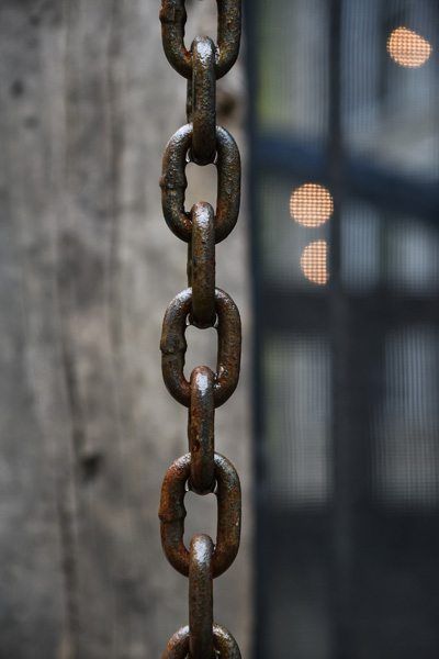 A close up of a rusty chain hanging from a fence.