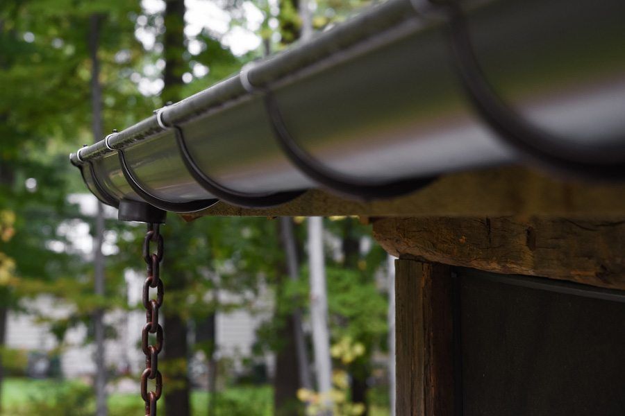 A close up of a metal gutter with a chain hanging from it.