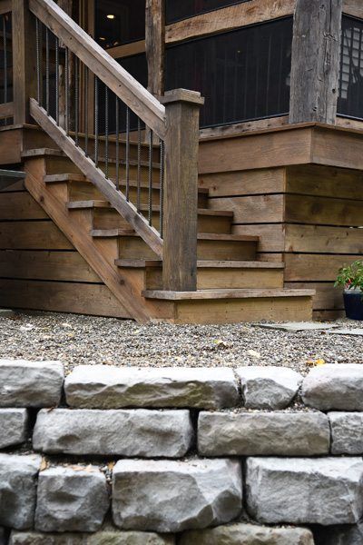 A wooden deck with stairs and a stone wall