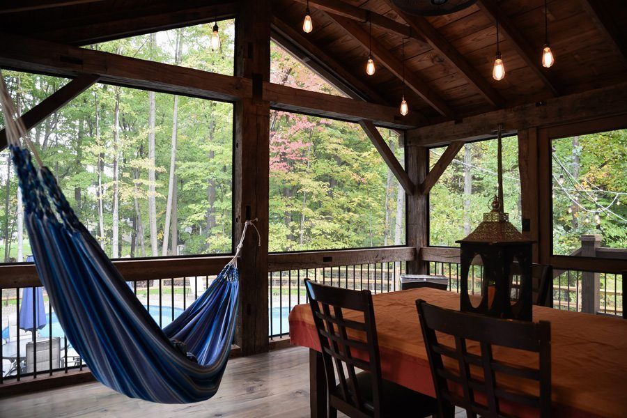 A screened in porch with a hammock and a table.