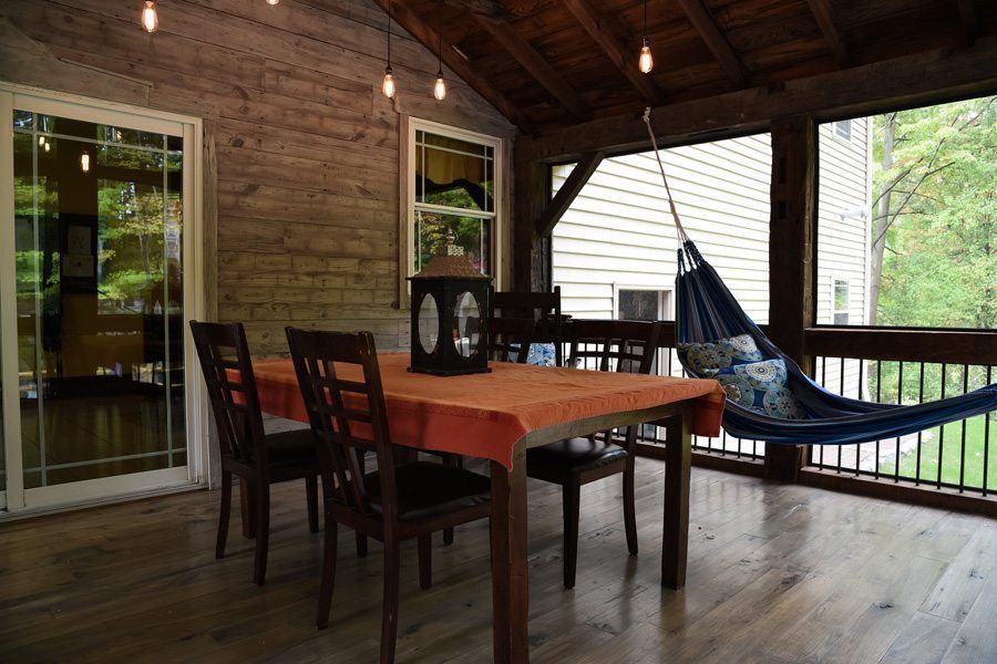 A screened in porch with a table and chairs and a hammock.