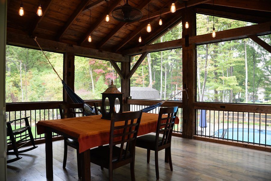 A screened in porch with a table and chairs and a hammock.