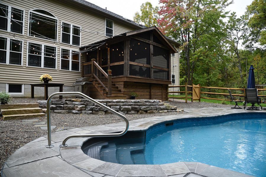 A large house with a screened in porch and a swimming pool in front of it.