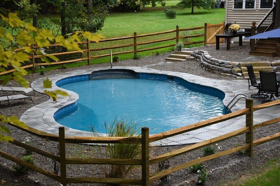 A large swimming pool surrounded by a wooden fence in a backyard.