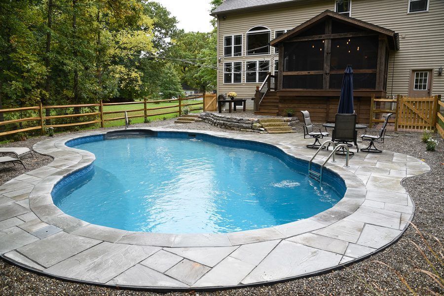 A large swimming pool is in the backyard of a house.