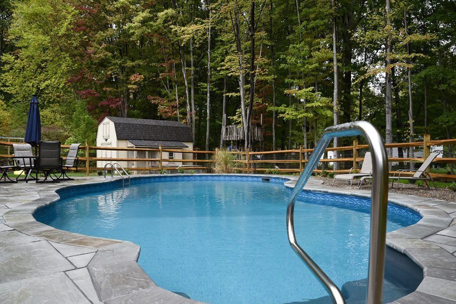 A large swimming pool surrounded by trees and chairs