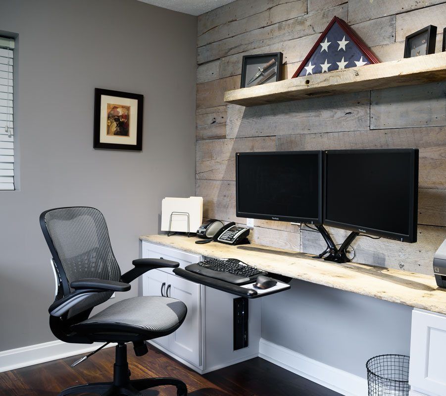 A home office with two computer monitors and a chair
