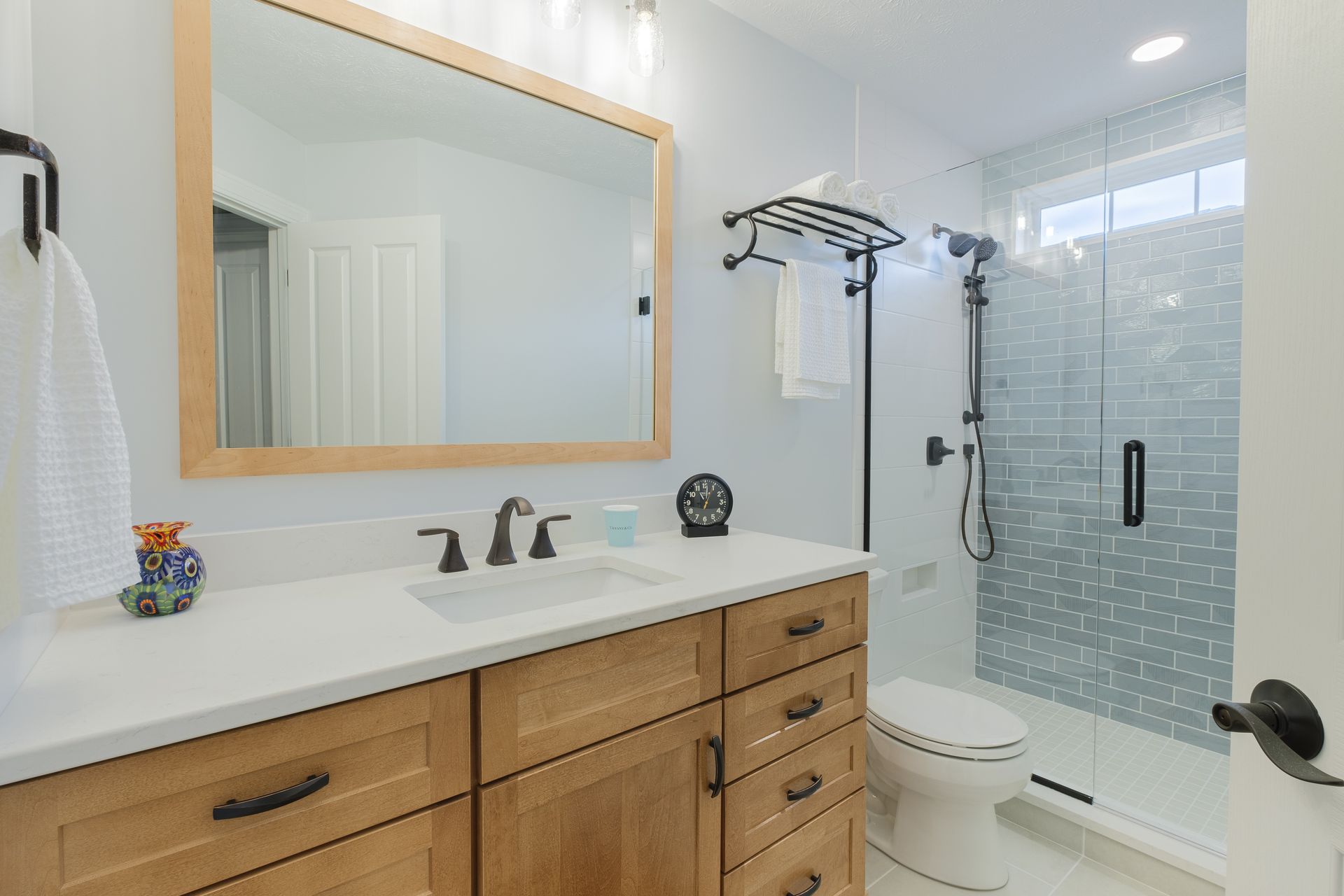 A bathroom with a toilet , sink , mirror and shower.