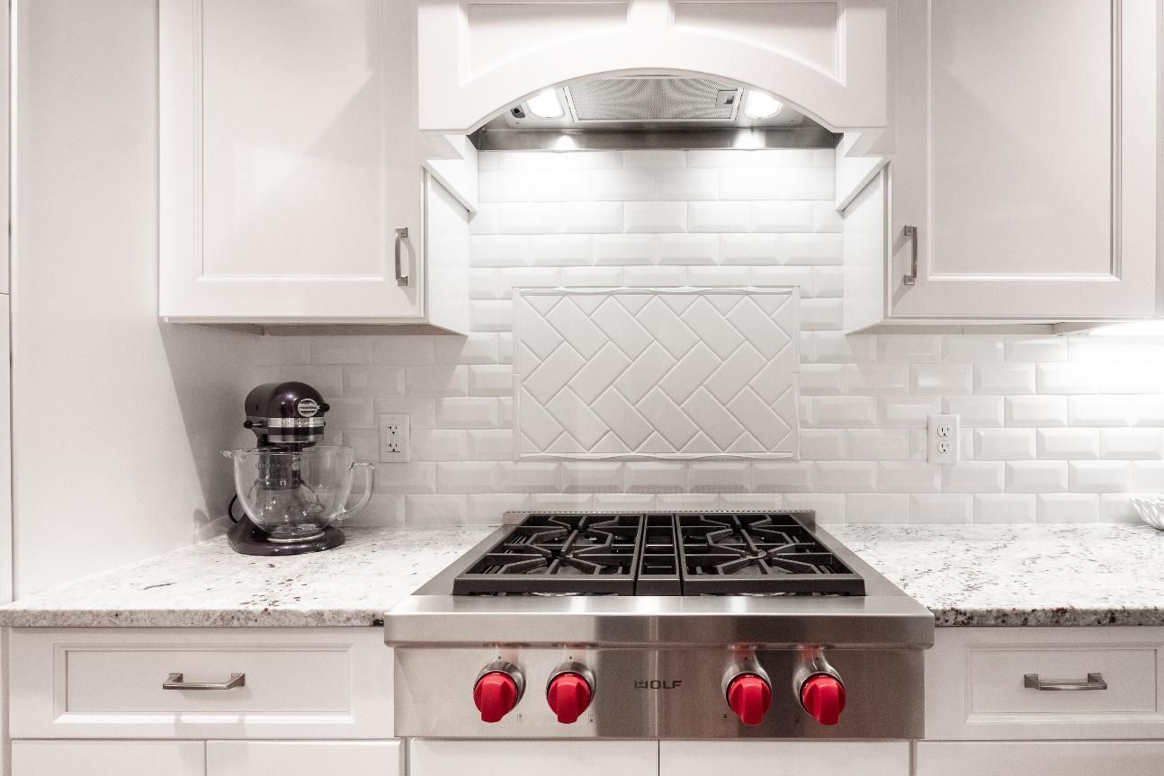 A kitchen with a stove top oven and a mixer on the counter.