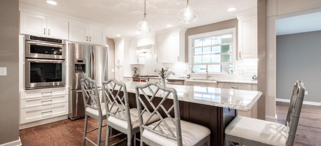 A kitchen with white cabinets , stainless steel appliances , granite counter tops and a large island.
