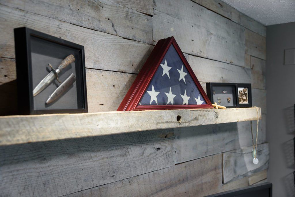 A wooden shelf with a flag and knives on it