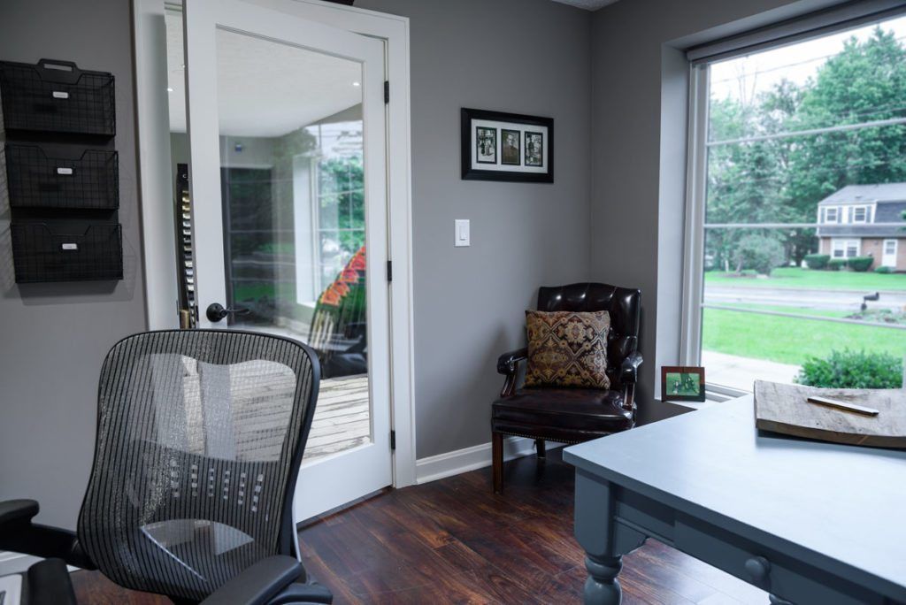A home office with a desk , chair , and large window.