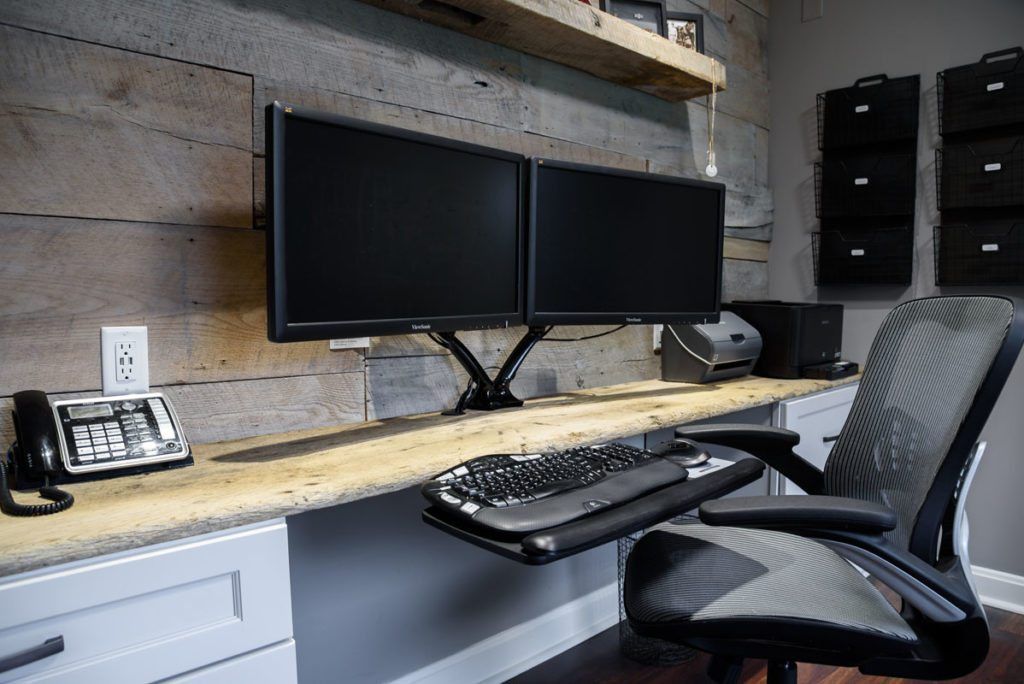 A desk with two monitors , a keyboard , and a phone on it.