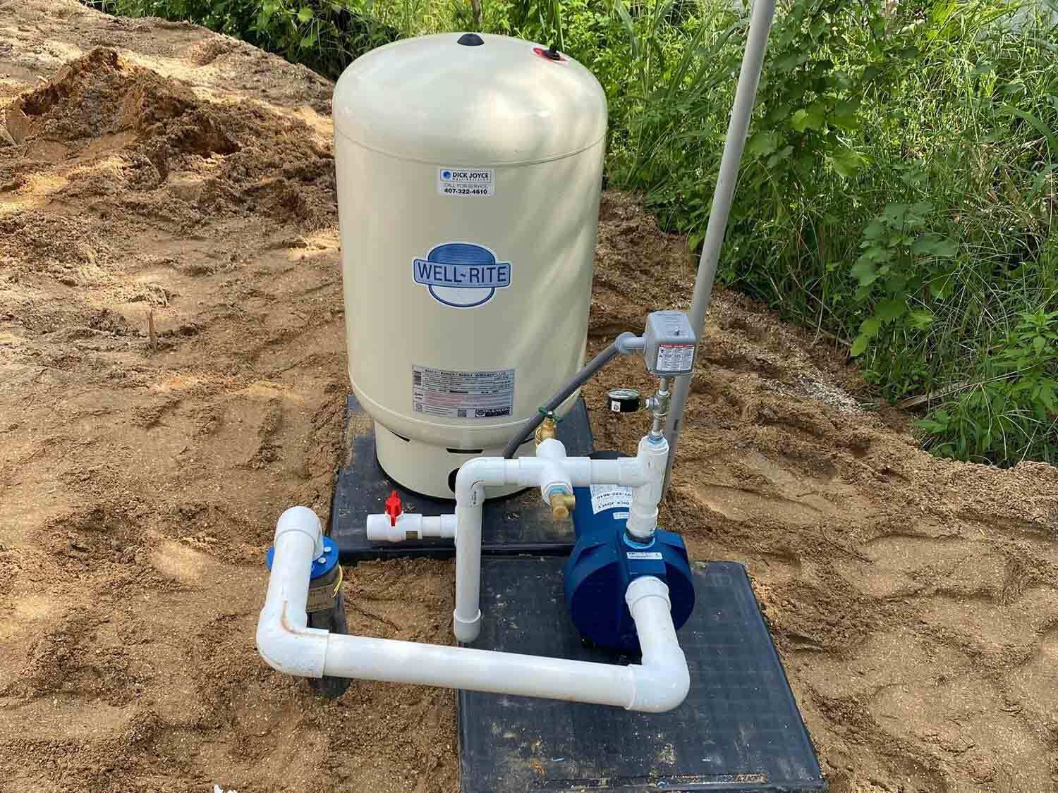 A water pump is sitting on top of a black box in the dirt.