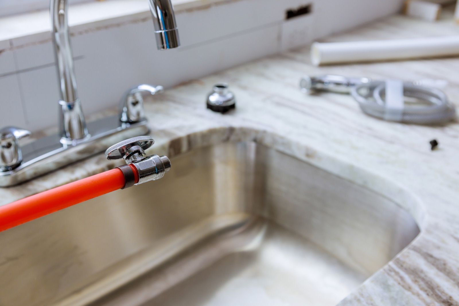 A kitchen sink with a red hose attached to it.