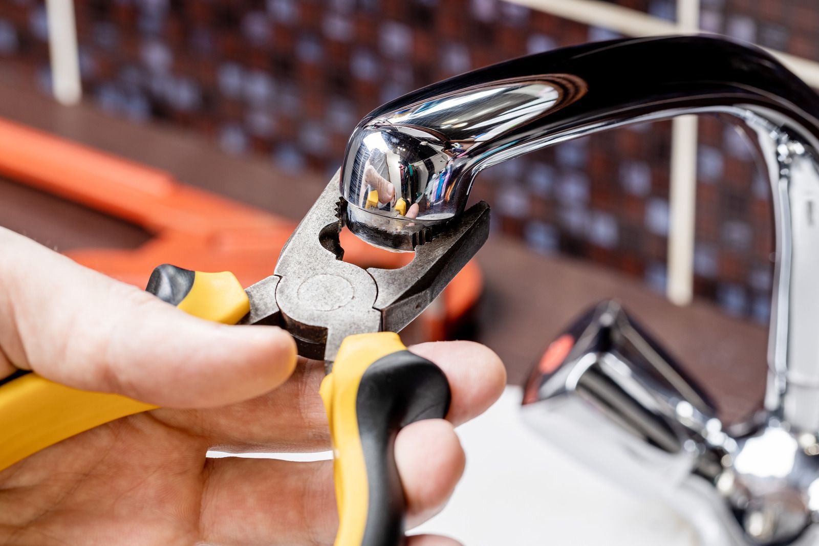 A person is fixing a faucet with pliers.