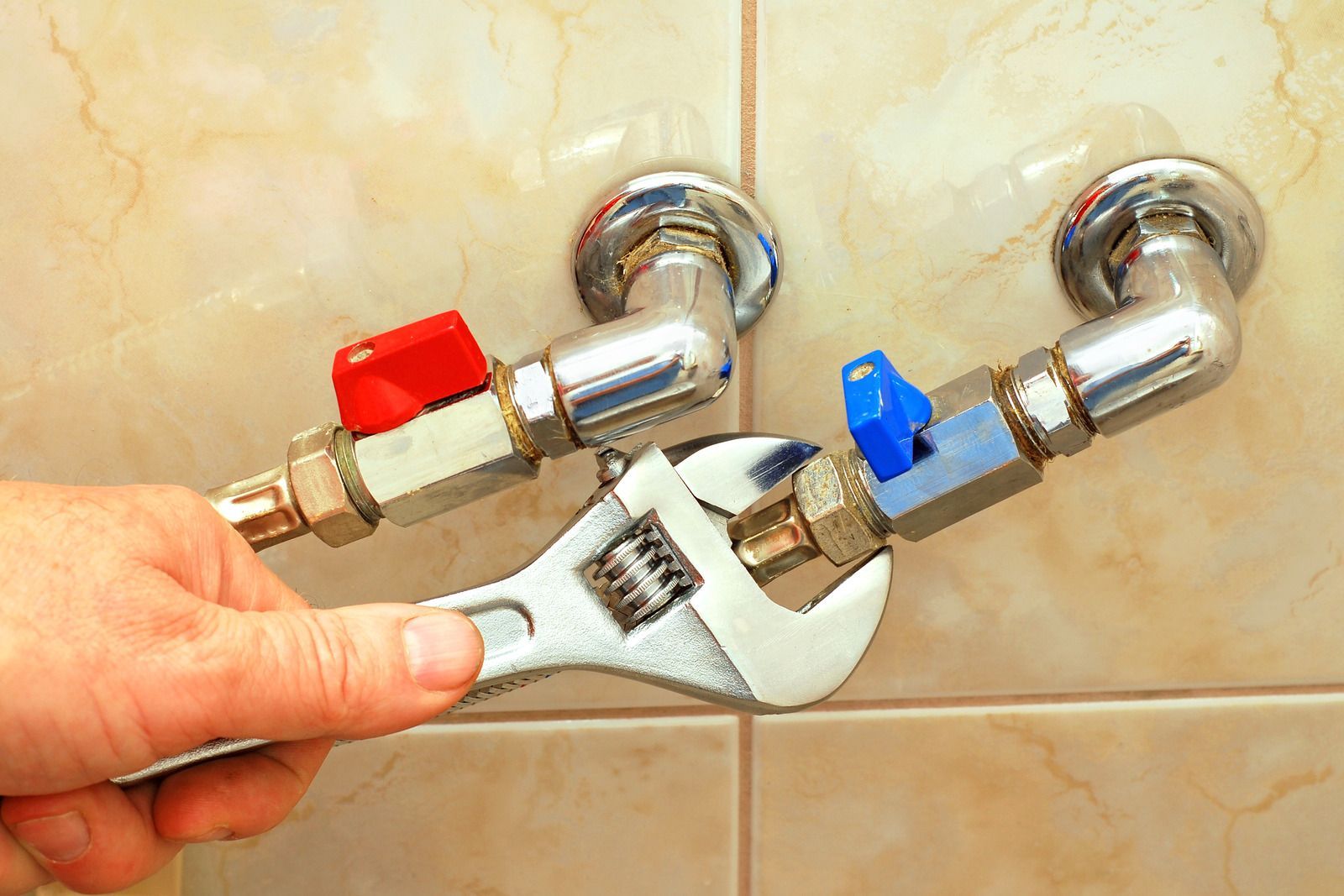 A person is fixing a faucet with a wrench.
