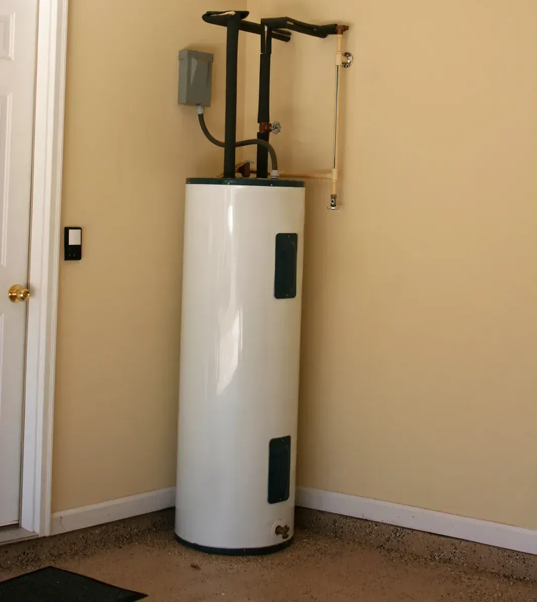 A white water heater is sitting in the corner of a room