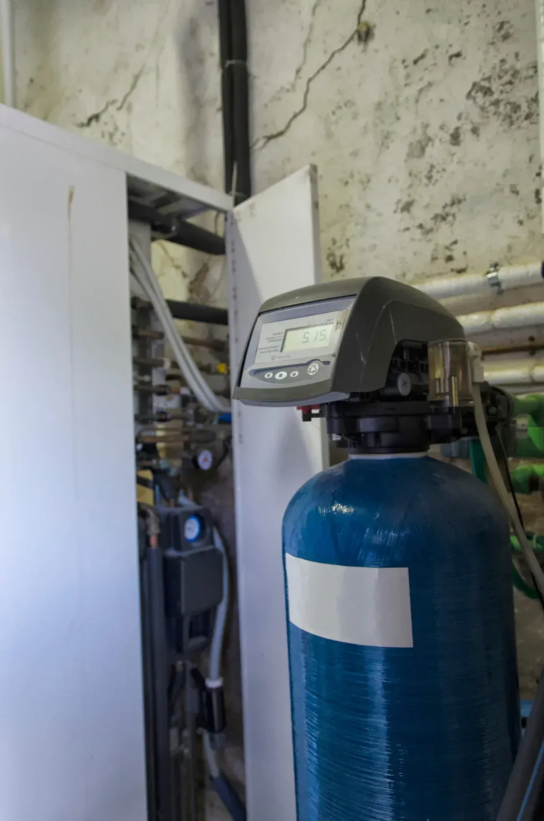 A blue water filter is sitting in a room next to a wall.
