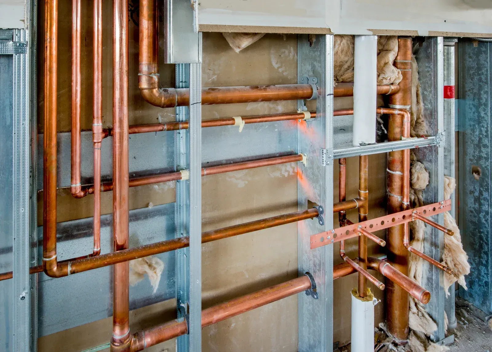 A wall with a lot of copper pipes hanging from it.