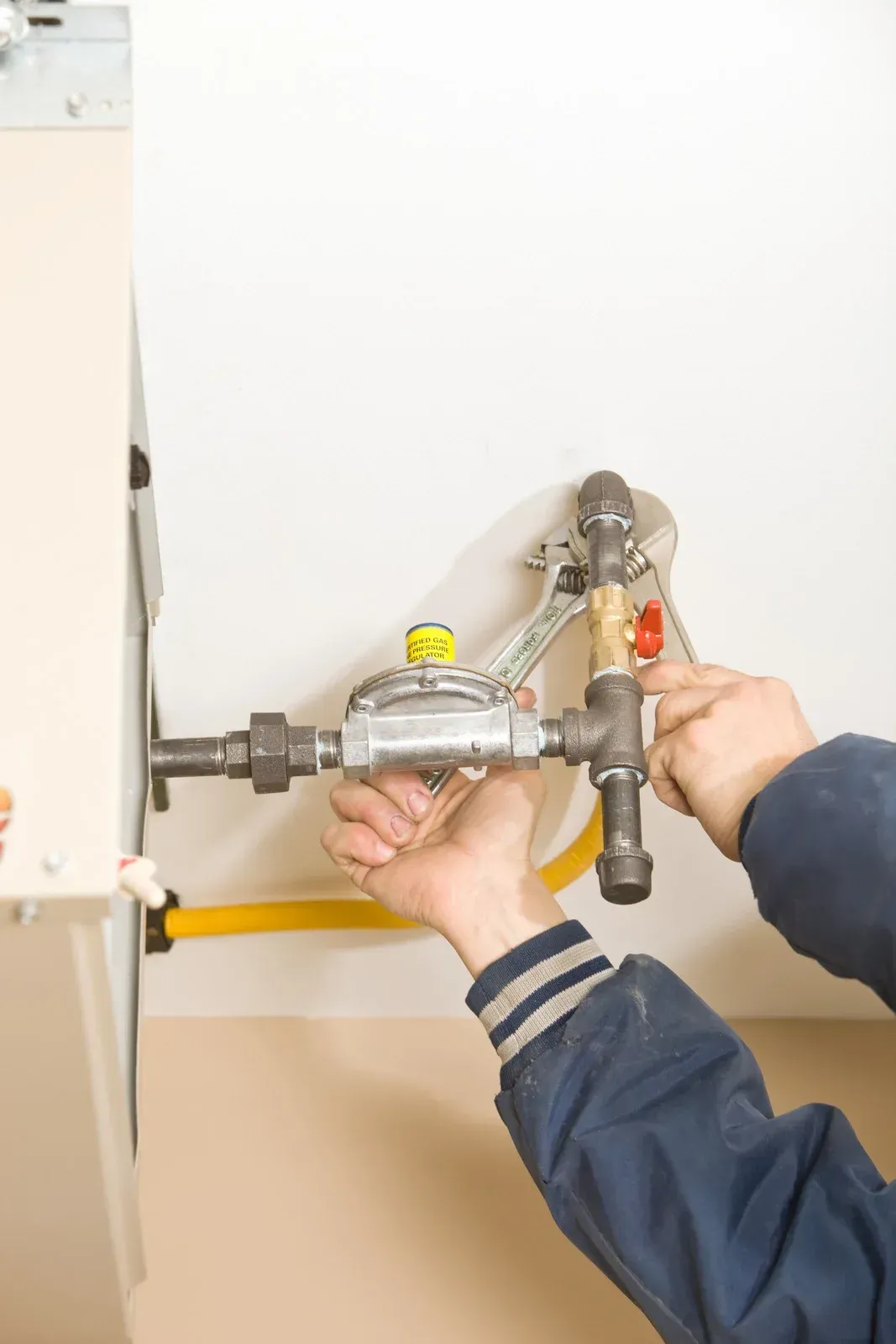 A person is fixing a gas pipe with a wrench.