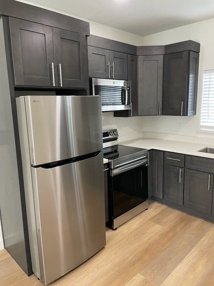 A kitchen with stainless steel appliances and gray cabinets.