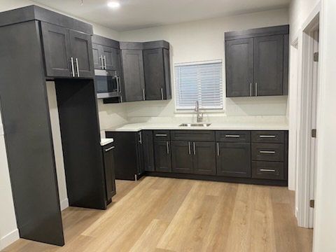 A kitchen with gray cabinets and wooden floors in a house.