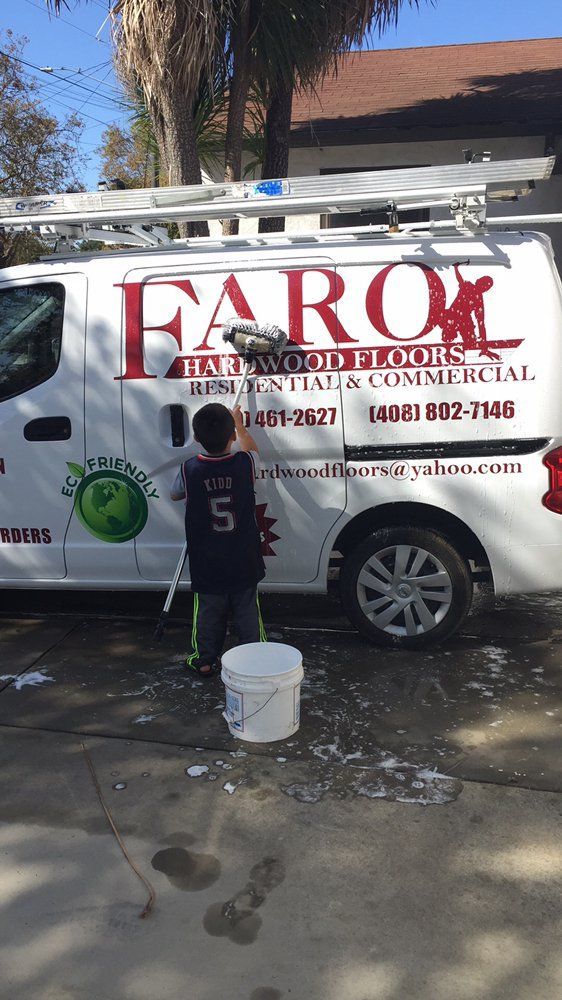A boy is washing a white van with the word farol on it
