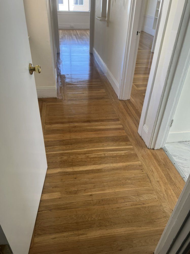 A hallway with hardwood floors and white walls in a house.