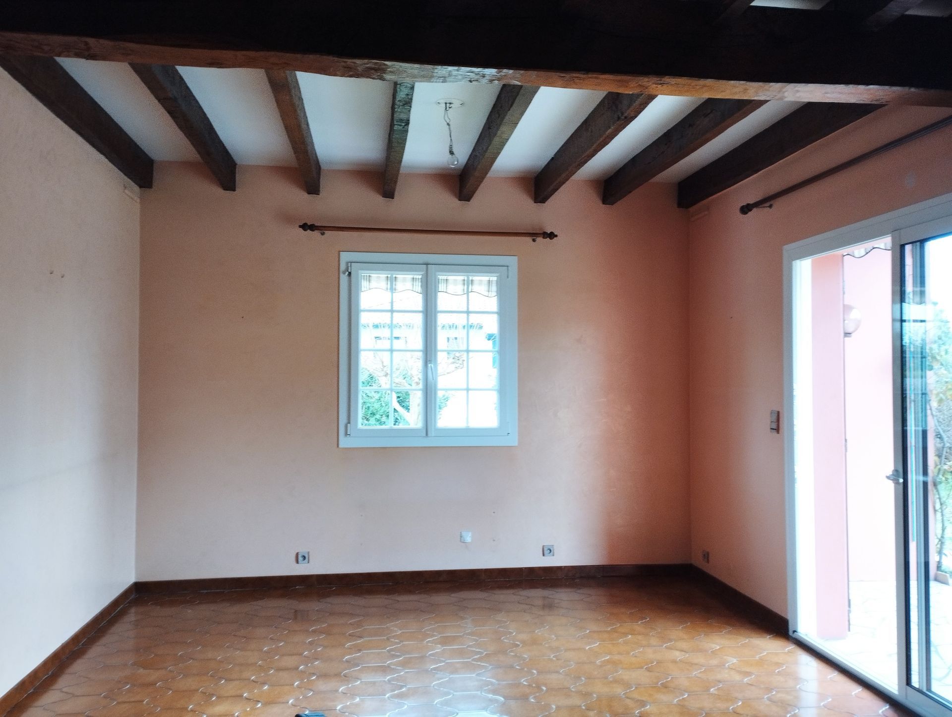 salon couleur saumon et poutres en bois sombre