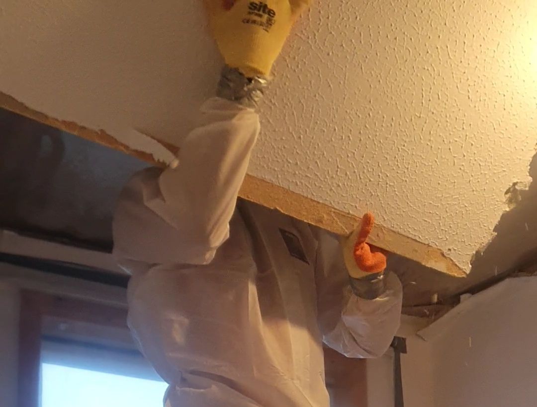 a person wearing safety gloves is working on a ceiling
