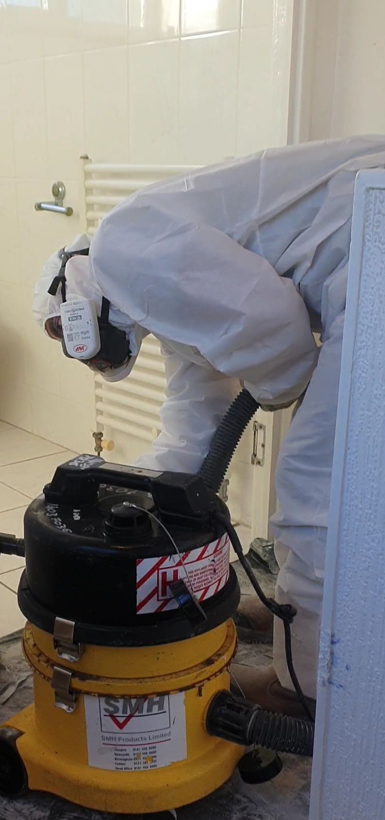 a man in a white suit is using a yellow vacuum cleaner