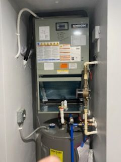 HVAC unit with water heater in a narrow closet; pipes and electrical components visible.