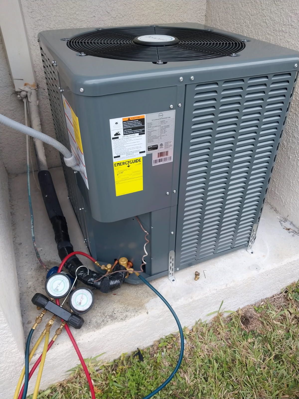 HVAC unit being serviced outdoors; gauges attached to refrigerant lines.