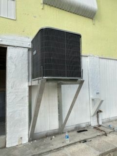 Air conditioning unit mounted on a metal bracket on the exterior of a building.