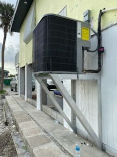 AC unit mounted on concrete support brackets on building exterior.
