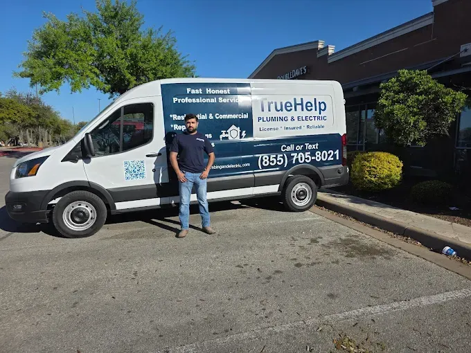 TrueHelp service van parked outside a building, with a man standing beside it.