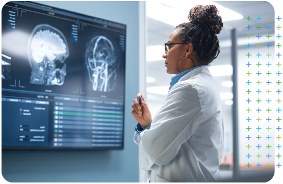 a secondary care doctor is looking at an x-ray of a brain on a large screen .