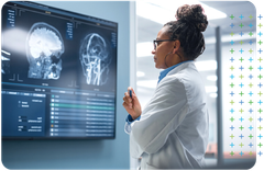 a female secondary care doctor is looking at an x-ray of a brain on a large screen .