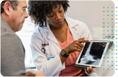 an Orthopaedic doctor is showing a patient an x-ray on a tablet .