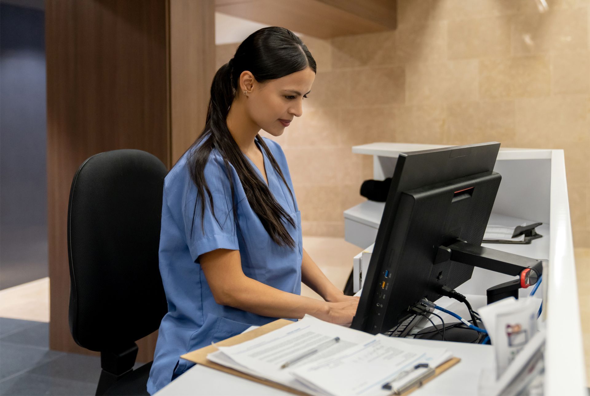 a nurse is sitting at a desk in front of a computer exploring MSK automation.