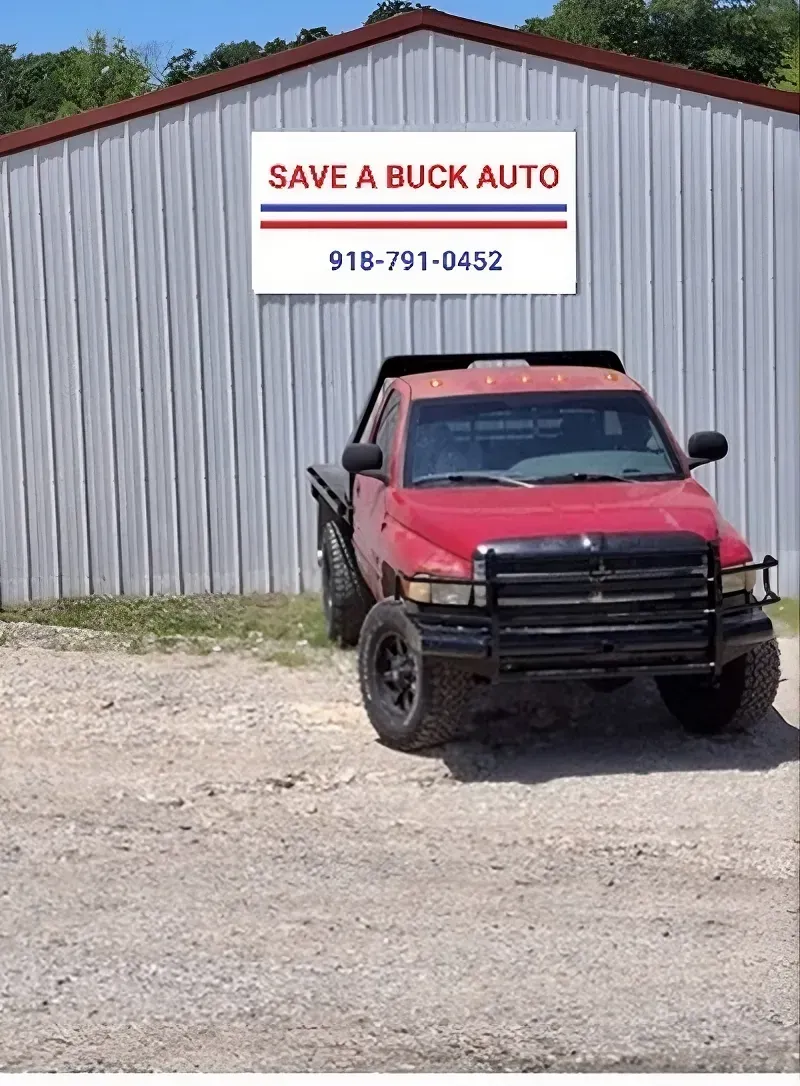 Red truck parked in front of a Save A Buck Auto shop with a phone number on a sign. | Save A Buck Auto